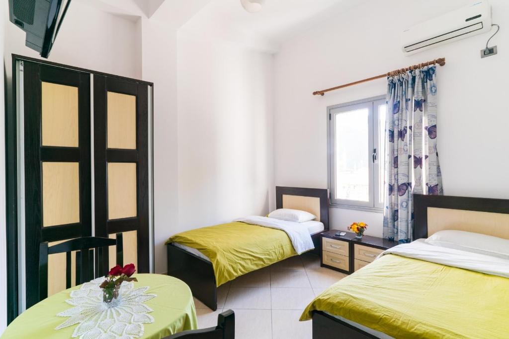 a room with two beds with yellow sheets and a window at Hotel Shpetimi in Çorovodë