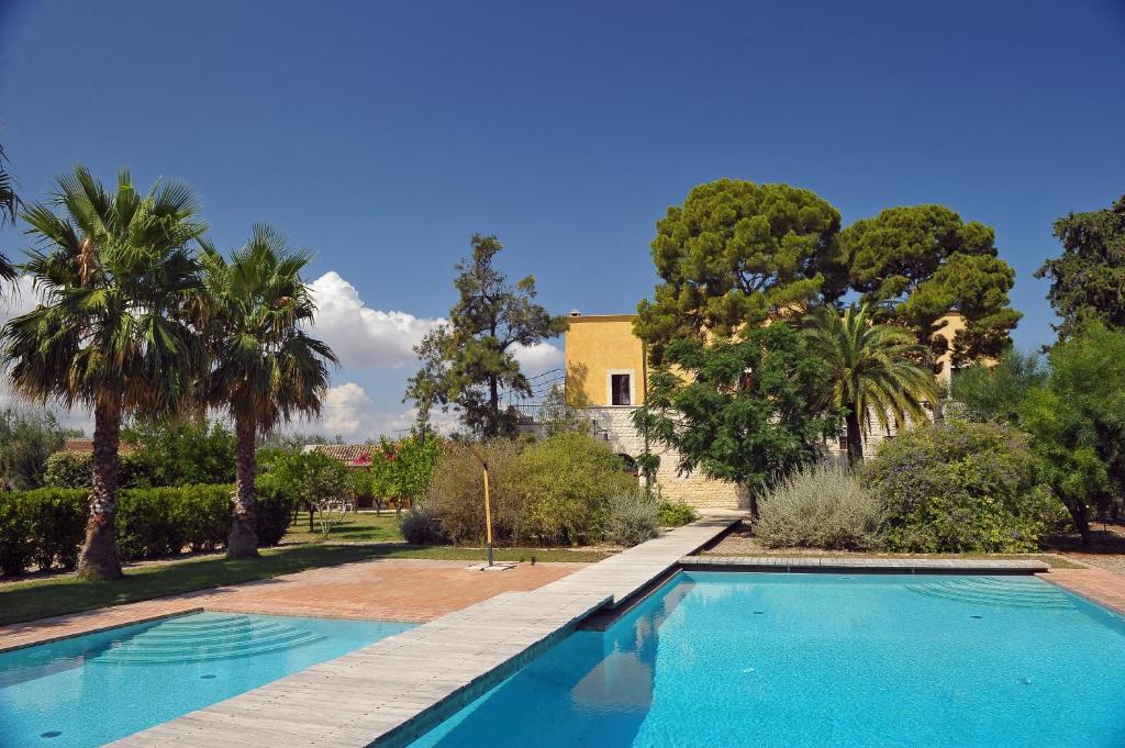 a swimming pool in front of a house with palm trees at Villa Carcano in Trani