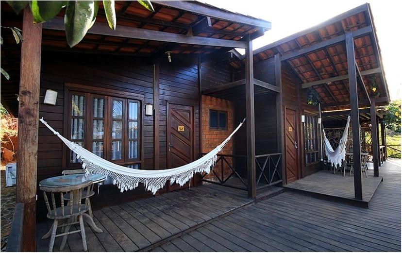 a porch of a wooden house with a hammock on it at Pousada Capim Açu in Fernando de Noronha