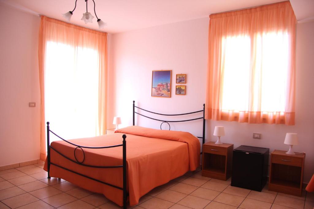 1 dormitorio con 1 cama con sábanas de color naranja y ventanas en Fragolina B&B, en Furci Siculo