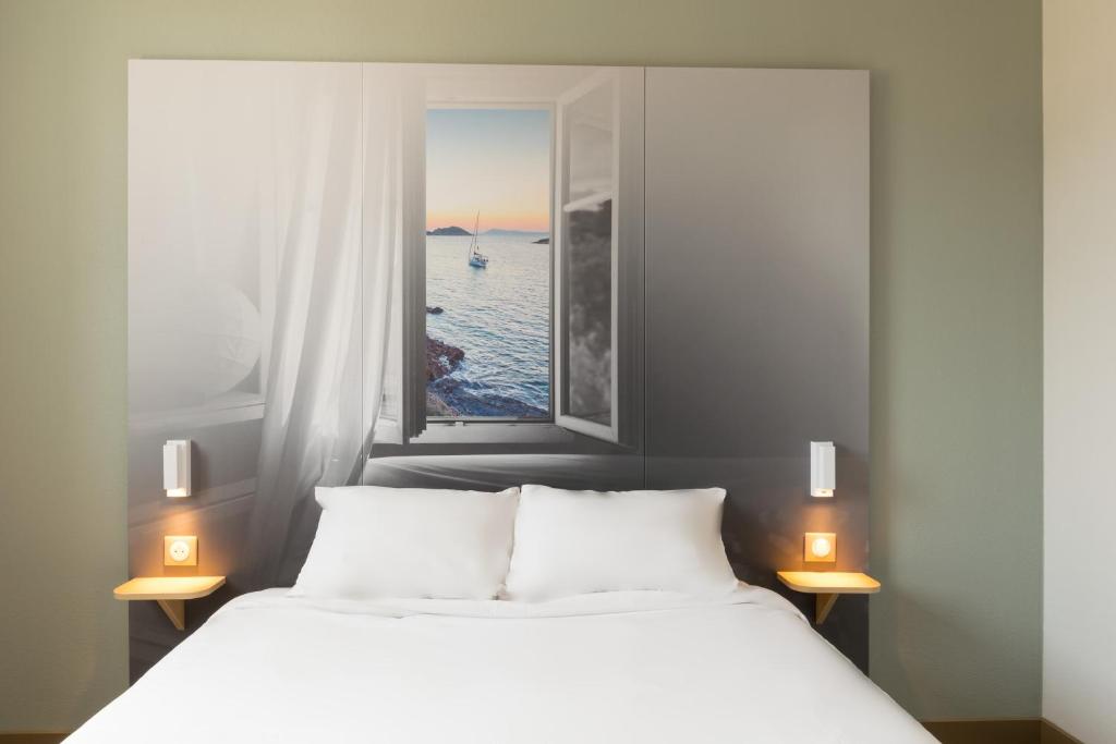 a bedroom with a white bed with a window at B&B HOTEL Marseille Aéroport Saint-Victoret in Saint-Victoret