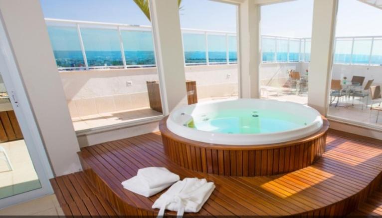 a large bathroom with a large tub with a view of the ocean at Apart Hotel Saint Moritz - Centro de Brasília in Brasilia