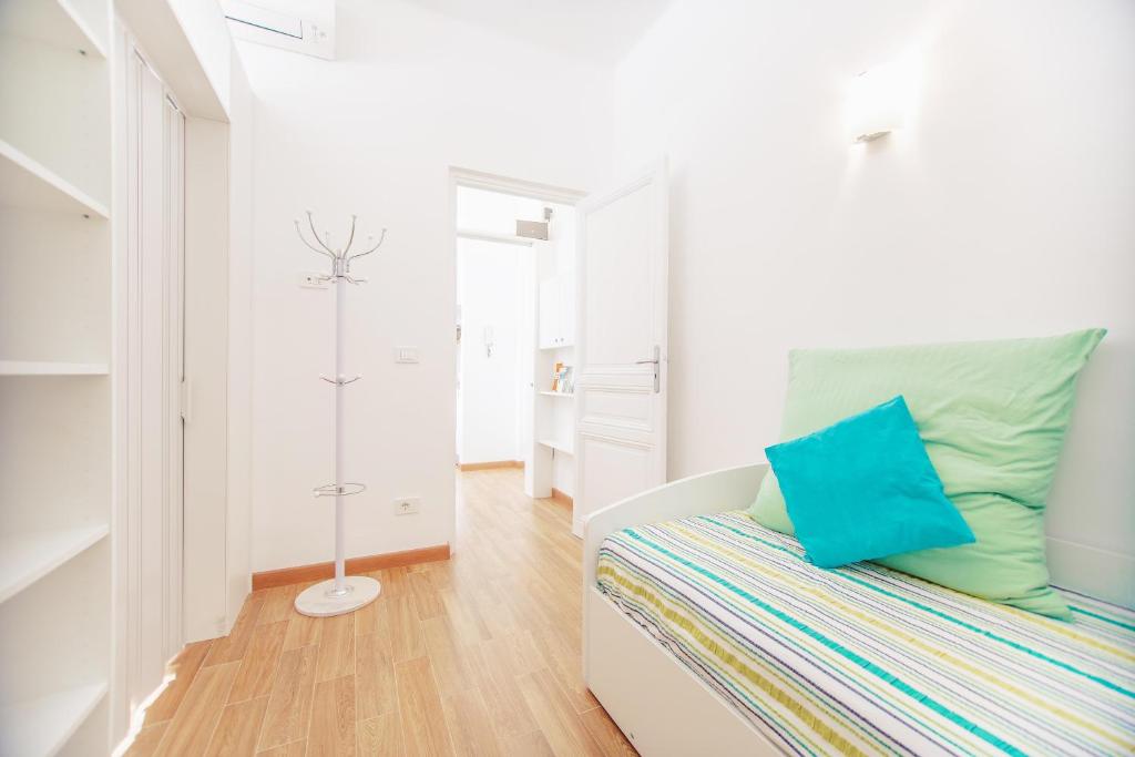 a white room with a bed with a blue pillow at Cuore di Sanremo apartment and free parking in Sanremo