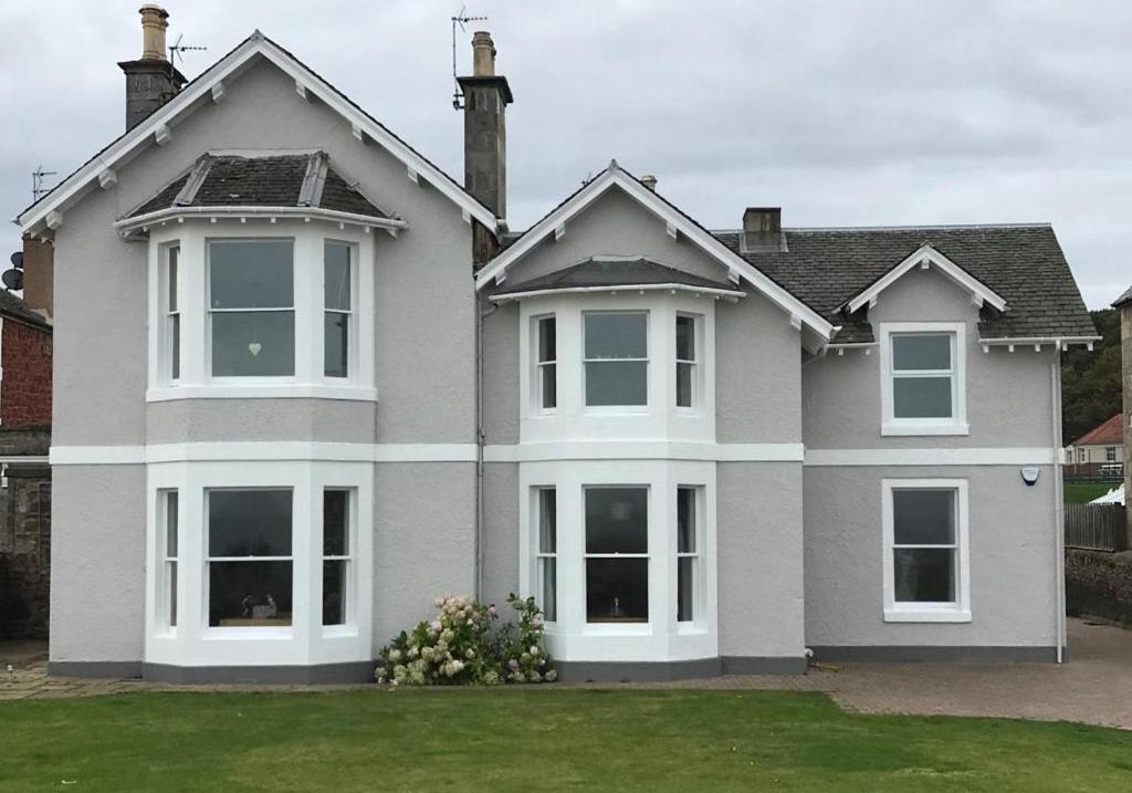 a gray house with white windows and a yard at Firth View in North Berwick