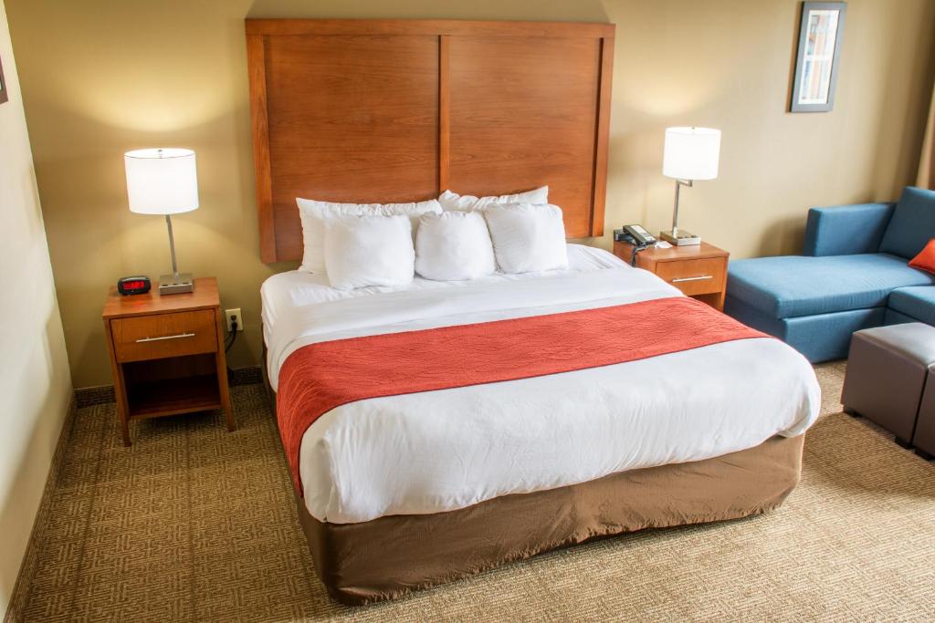 a hotel room with a large bed and a blue couch at Comfort Inn in Dickson