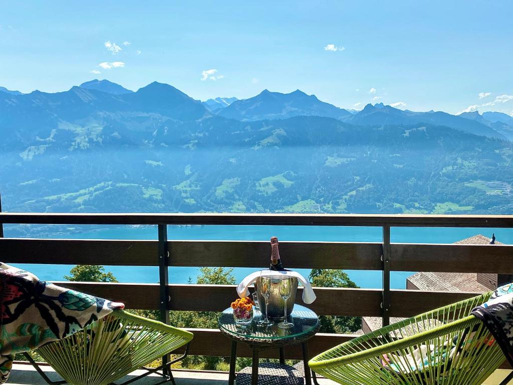 a table with a tea kettle on a balcony with mountains at Hotel Gloria in Beatenberg