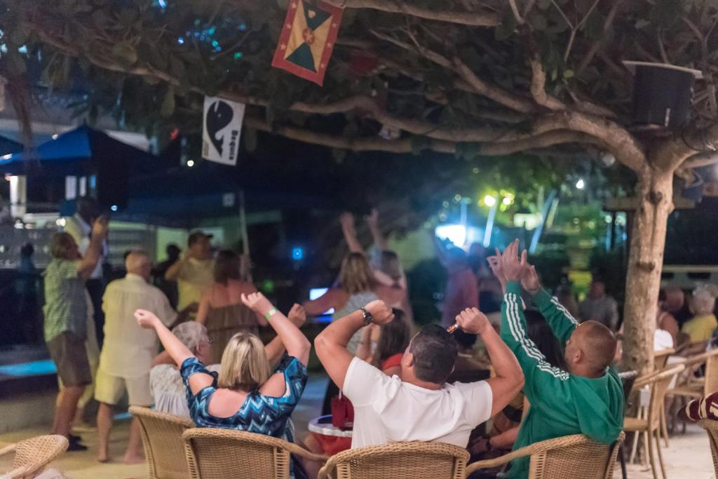 a group of people sitting in chairs with their hands in the air at Coconut Court Beach Hotel in Bridgetown