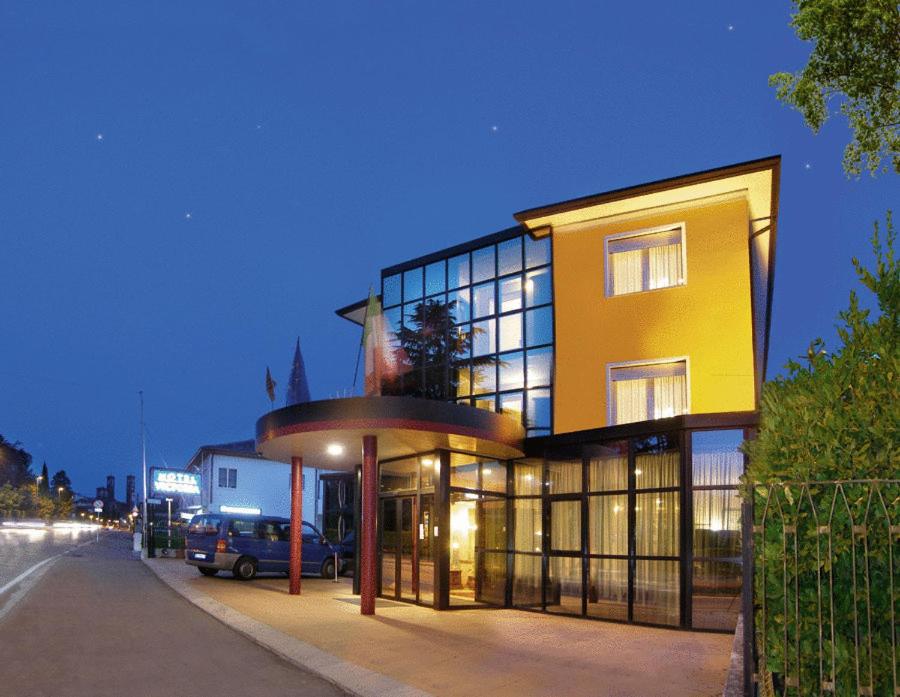 een groot geel gebouw met ramen aan een straat bij Hotel Victoria in Bassano del Grappa