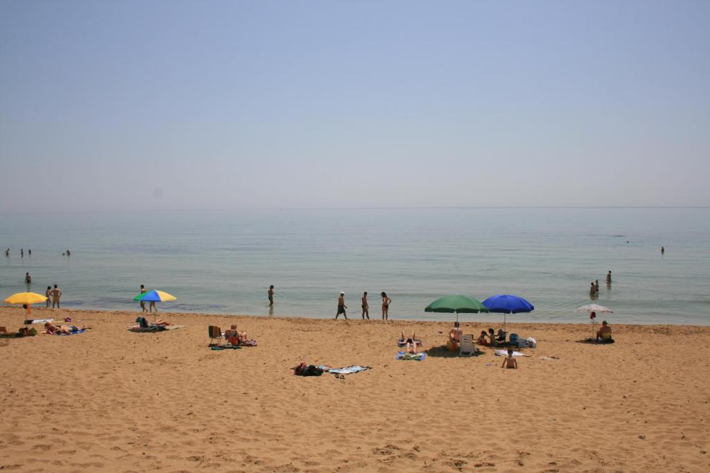 a group of people on a beach with umbrellas at Lido di Noto Villa Cocus Apartment Vista Mare in Noto Marina