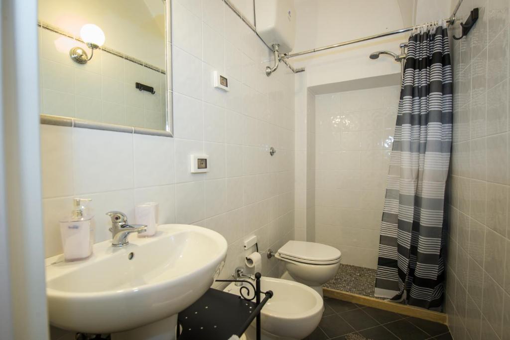 un bagno con lavandino, water e specchio di Bed and Breakfast La Torretta a Gaeta