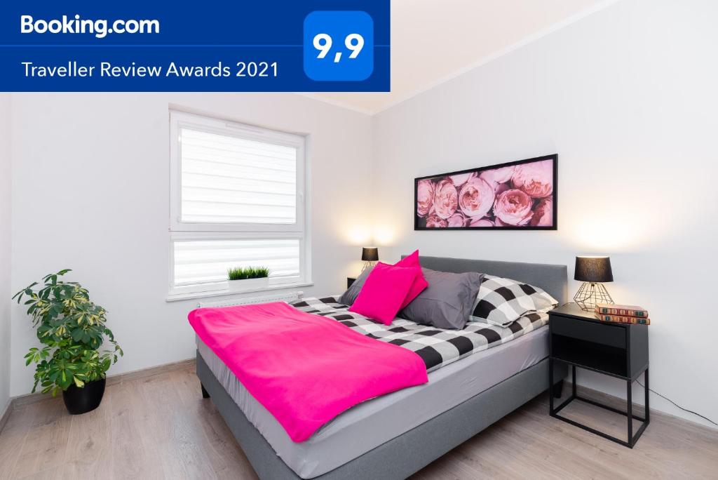 een slaapkamer met een bed met een roze deken bij Apartment Antonio in Gdańsk