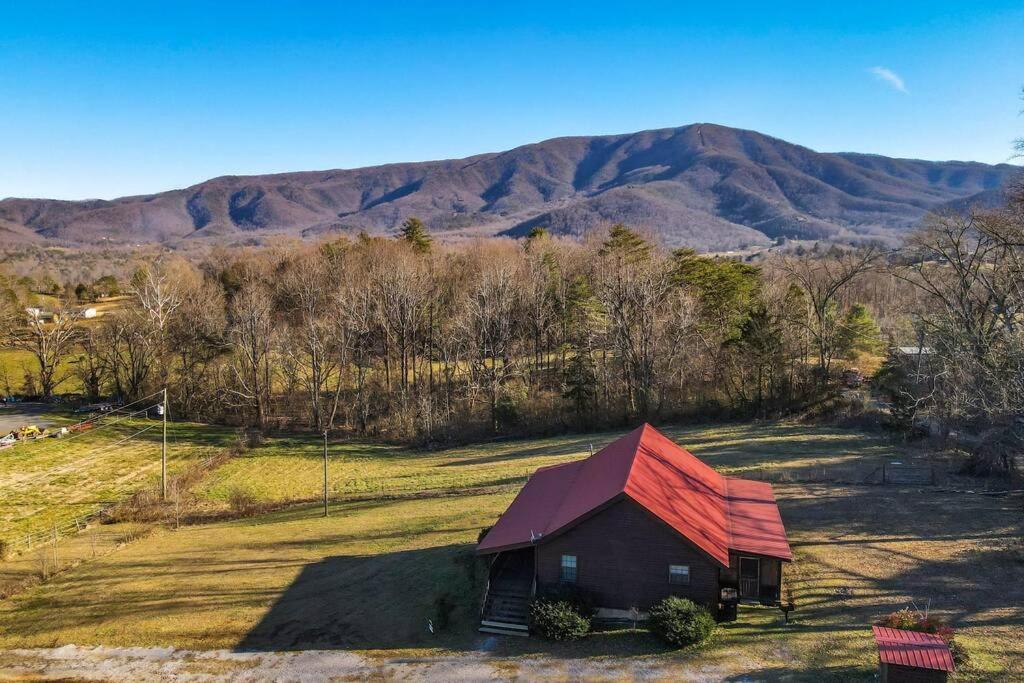 un granero rojo en un campo con montañas al fondo en Beautiful View! Log cabin,Fireplace,Hot Tub,Arcade,Pool,Fishing en Sevierville