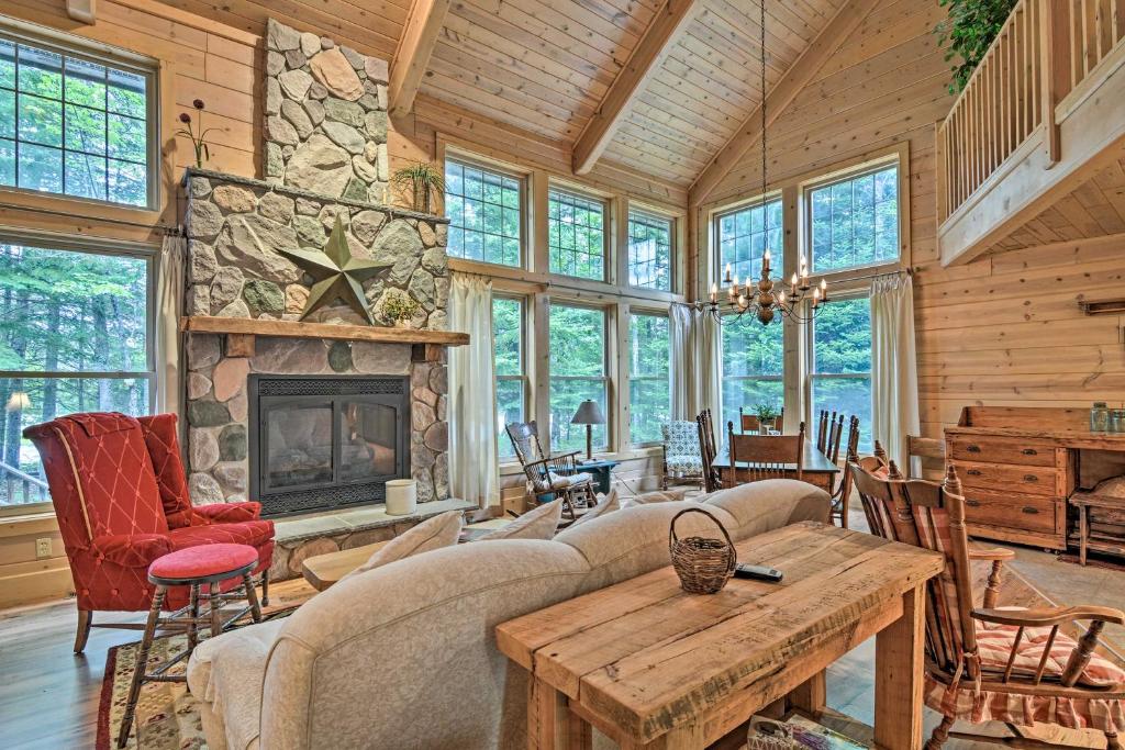 a living room with a stone fireplace in a house at Rustic and Modern Home with Fire Pit on Tower Pond! in Onaway