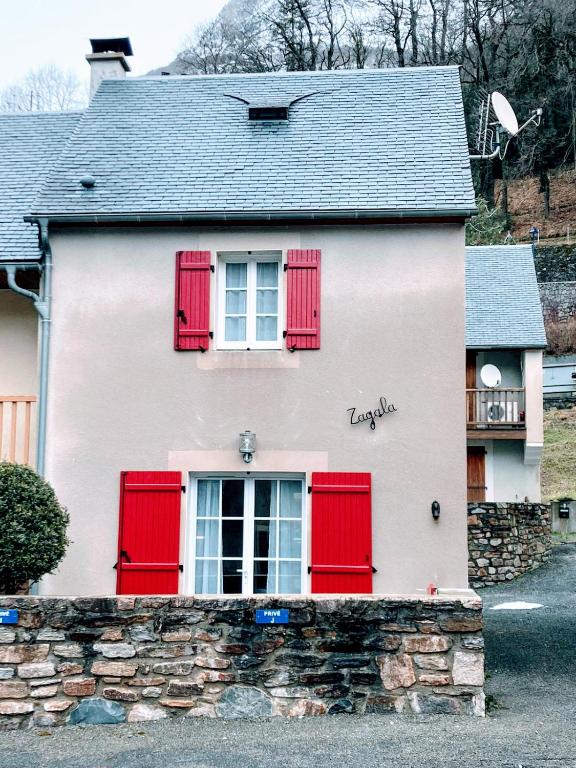 une maison blanche avec des volets rouges et un mur en pierre dans l'établissement ZAGALA LA MAISON DE LA MONTAGNE, à Gèdre