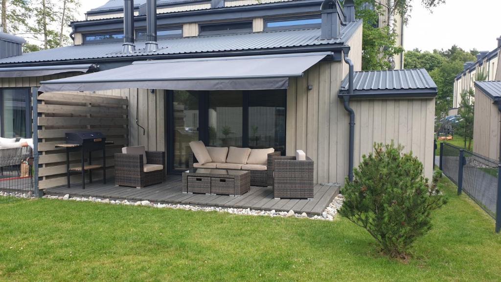 eine Terrasse mit einem Sofa und Stühlen auf einer Terrasse in der Unterkunft Nedidelis, jaukus namelis Palangoje, Čiki Puki in Palanga