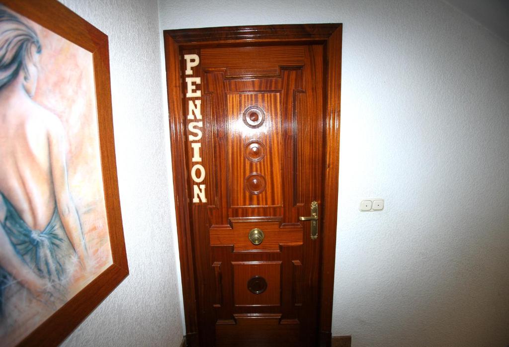 a wooden door in a room with a picture at Pensión Como en Casa in Rincón de Soto