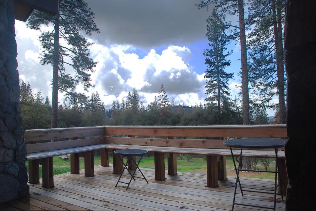 a wooden bench sitting on a deck with two tables at Sierra Trails Retreat in Mariposa