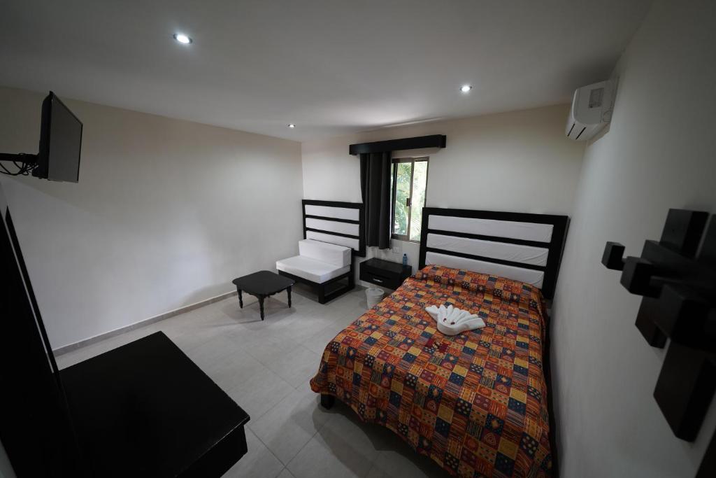 a bedroom with a bed and a chair and a television at Hotel Sevilla Palenque in Palenque