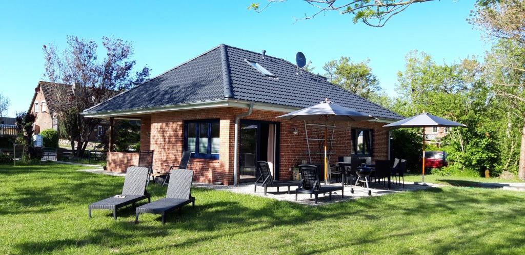 a small brick house with chairs and tables in the grass at Tante Käthe in Nordstrand