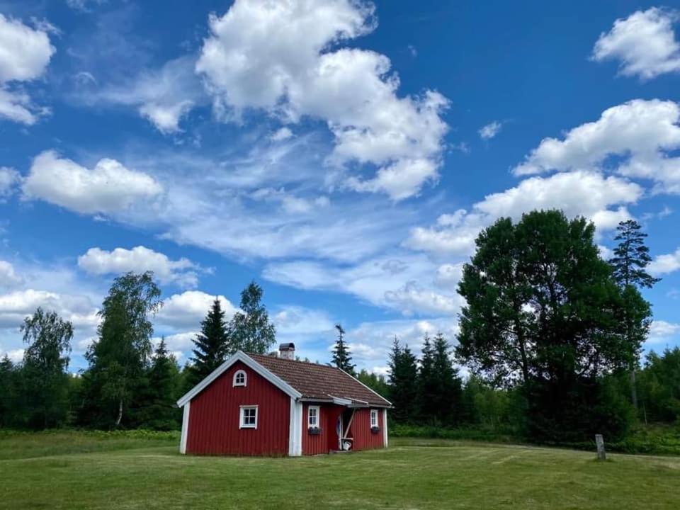 um celeiro vermelho num campo sob um céu nublado em Källåsens Stuguthyrning em Sjötofta