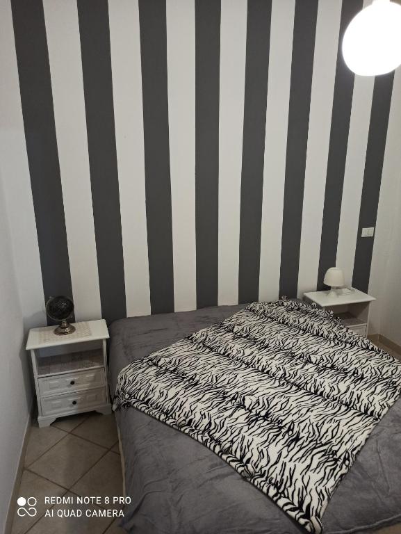 1 dormitorio con cama y paredes a rayas en blanco y negro en Sicilia bedda, en Isola delle Femmine
