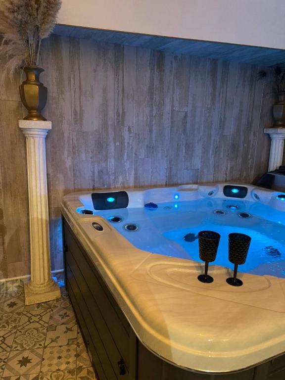 a jacuzzi tub with two wine glasses in it at Gîtes Spa en Baie de Somme in Grand-Laviers