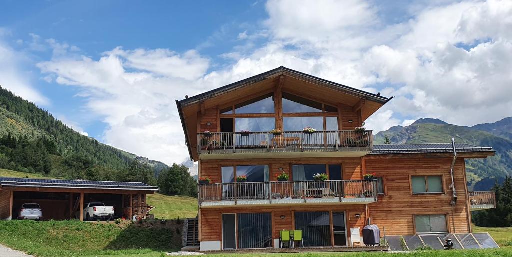Chalet Breithorn- Perfect for Holiday with Amazing View! في Obergesteln: منزل خشبي مع شرفة على تلة