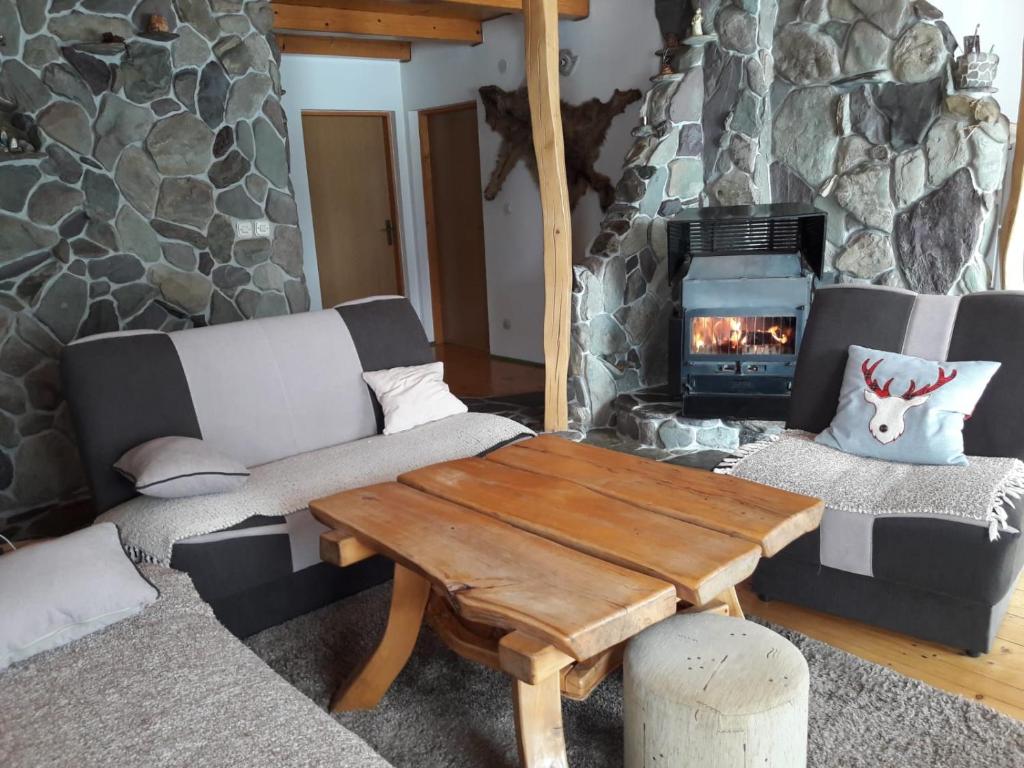ein Wohnzimmer mit einem Steinkamin und einem Holztisch in der Unterkunft Chalet Katy in Kupres