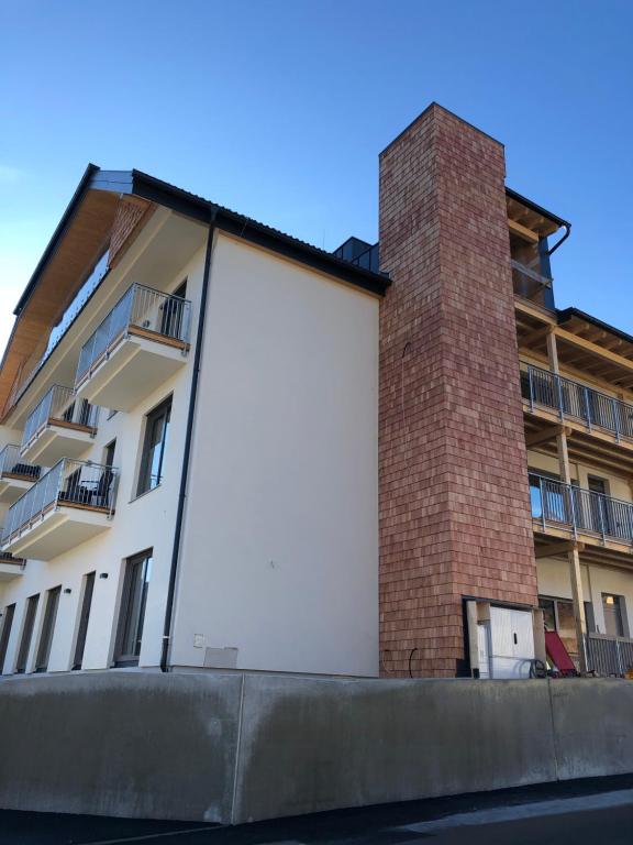 ein großes weißes Gebäude mit einem gemauerten Kamin in der Unterkunft Ski & Nature Apartment in Mauterndorf