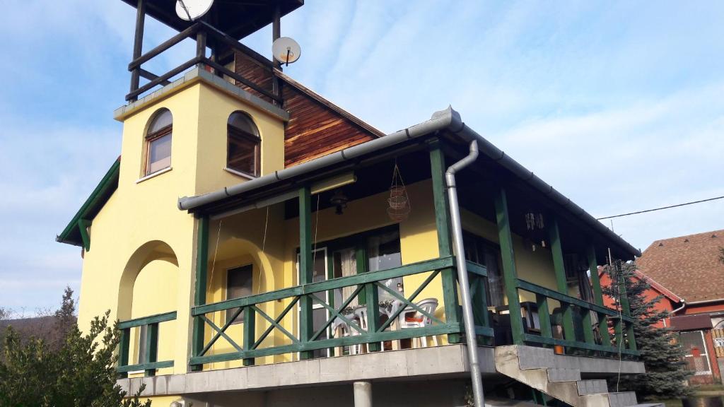 Csilla Nyaraló في سانت إندرا: مبنى اصفر وأخضر مع برج الساعة