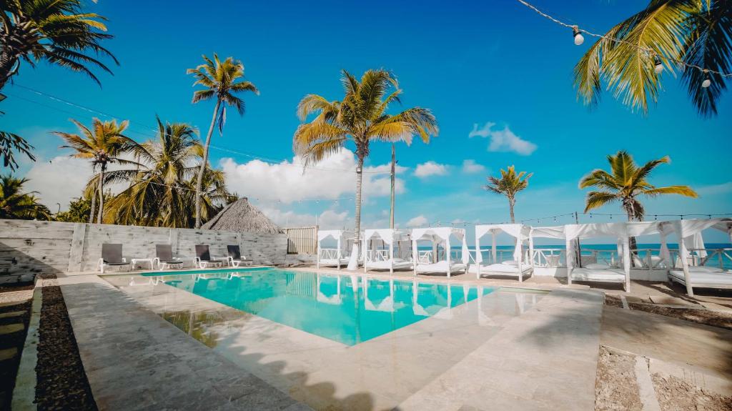 a resort swimming pool with chairs and palm trees at Hotel Marbelo Coveñas in Coveñas