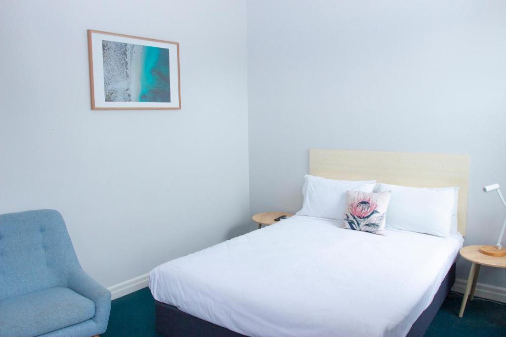 a bedroom with a bed and a blue chair at Grand Hotel Rockdale in Sydney