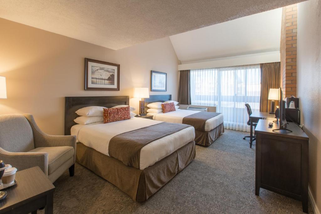 a hotel room with two beds and a chair at The Embassy Inn in Victoria