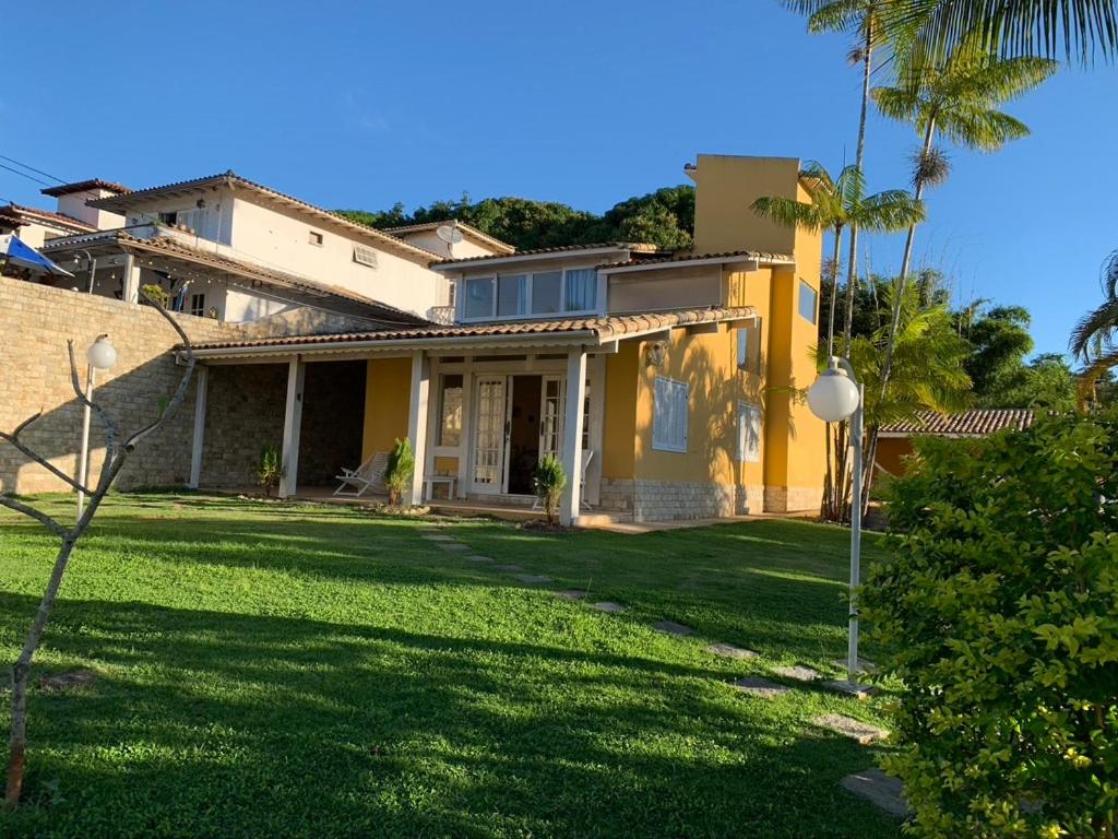 una casa con un patio con césped verde y palmeras en CASA NO CENTRO DE BUZIOS, en Búzios