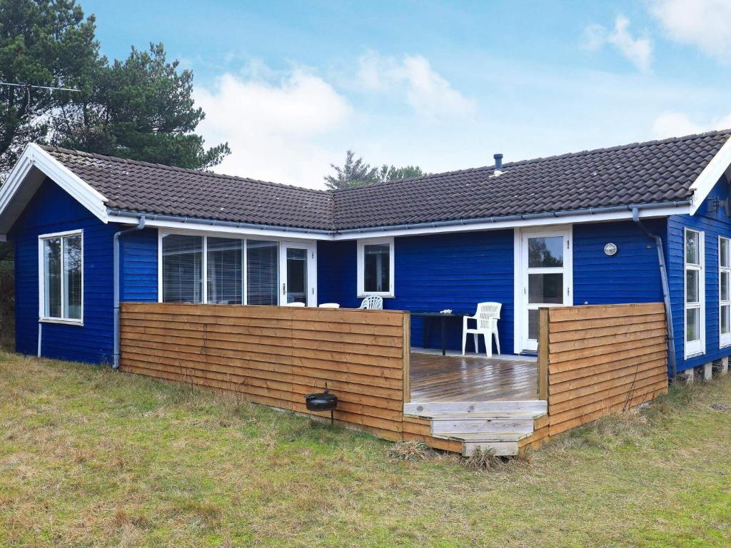 una casa azul con una terraza de madera delante de ella en 6 person holiday home in Fjerritslev, en Fjerritslev