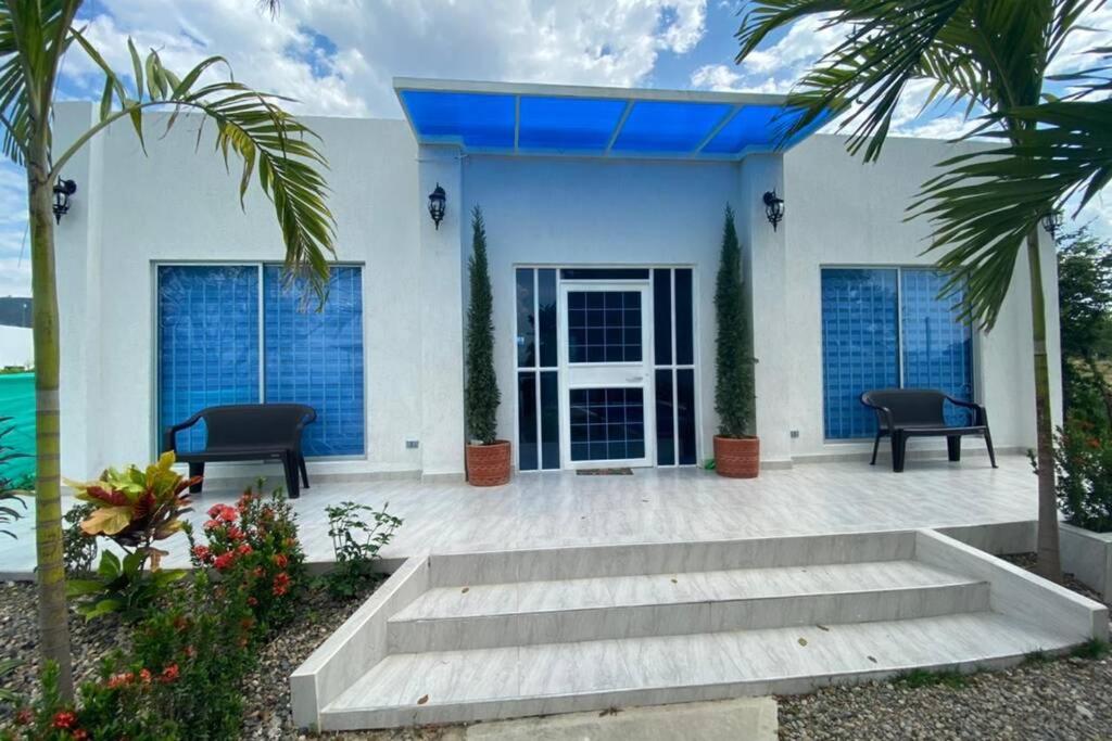 une maison blanche avec 2 chaises et une terrasse couverte dans l'établissement Casa campestre, Ricaurte Cundinamarca, à Ricaurte