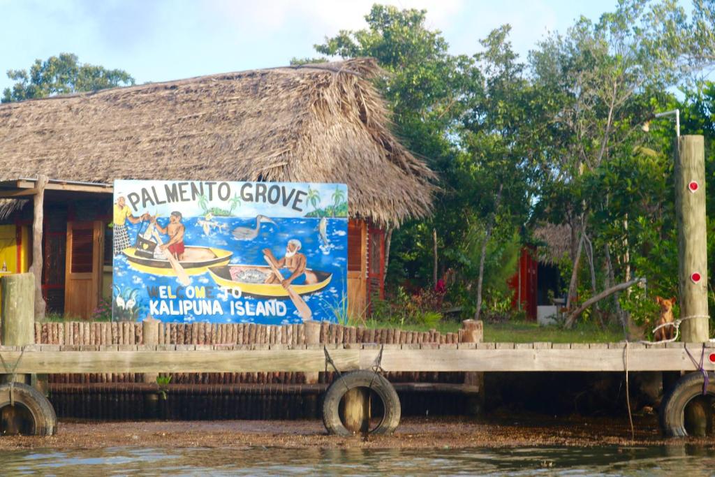 um sinal ao lado de uma casa na água em Palmento Grove Garifuna Eco-Cultural & Healing Institute em Hopkins
