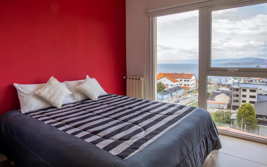 a bedroom with a red wall and a large window at Happy Guest Apart 36 in Ushuaia
