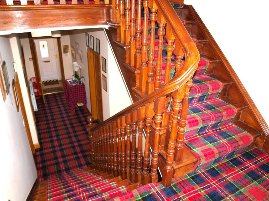 a wooden staircase with a plaid carpet at Knight's Rest Guest House in Airdrie