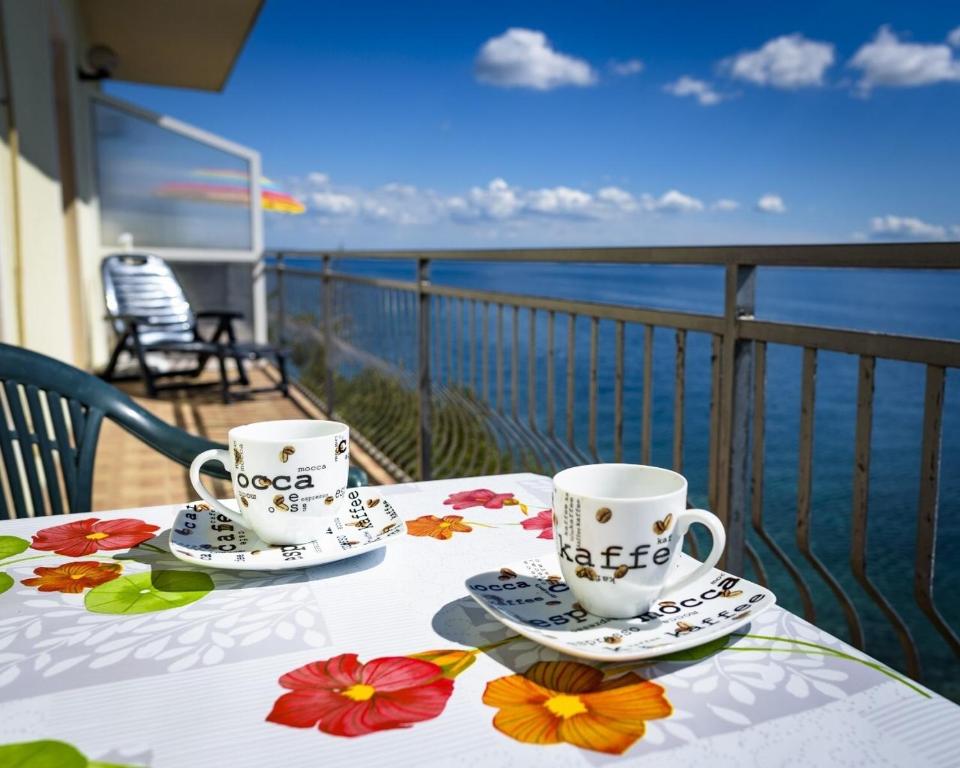 twee koffiekopjes op een tafel op een balkon bij Apartments Domagoj - on the beach in Lukovo Šugarje