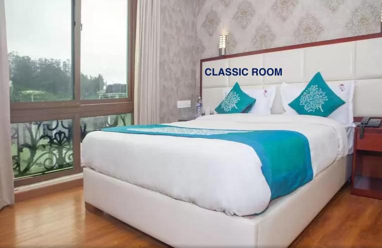 a large white bed in a room with a window at Hillcrest Metro in Ooty