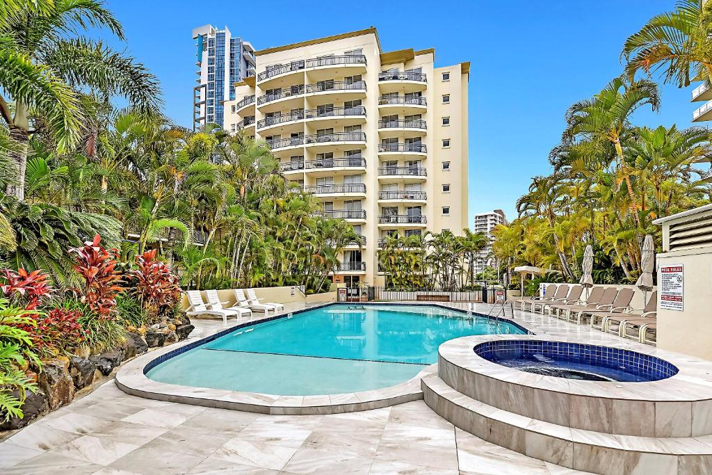 a swimming pool with chairs and a large building at Palazzo Colonnades in Gold Coast