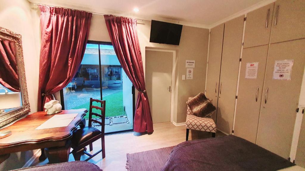 een woonkamer met een bureau, een tafel en een raam bij THE SPARE BEDROOM Unit 1 in Harrismith
