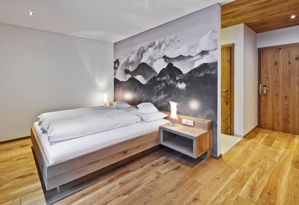 a bedroom with a large bed and a wall mural at Sporthotel Silvretta Montafon in Gaschurn