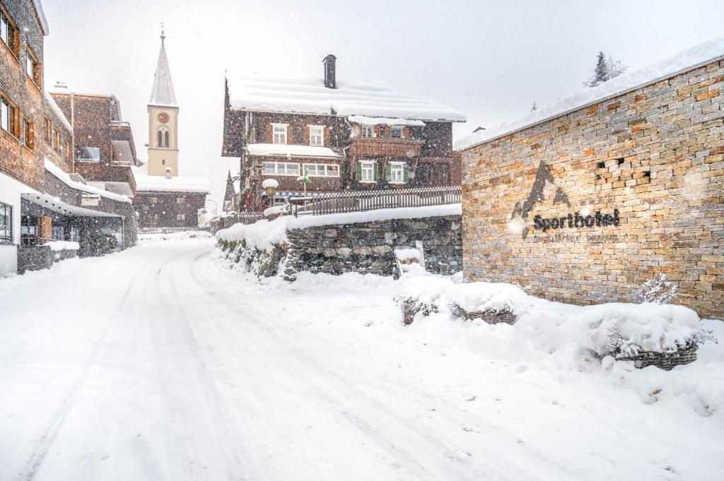 a snow covered street in a town with a building at Sporthotel Silvretta Montafon in Gaschurn