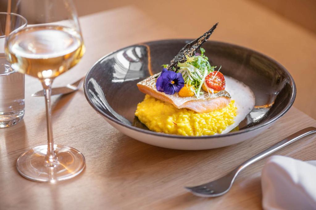 a bowl of food on a table with a glass of wine at Sporthotel Silvretta Montafon in Gaschurn