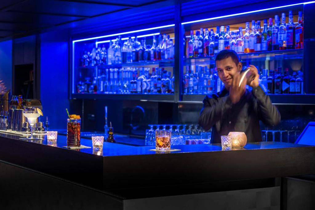 a man standing at a bar with a bunch of glasses at Sporthotel Silvretta Montafon in Gaschurn