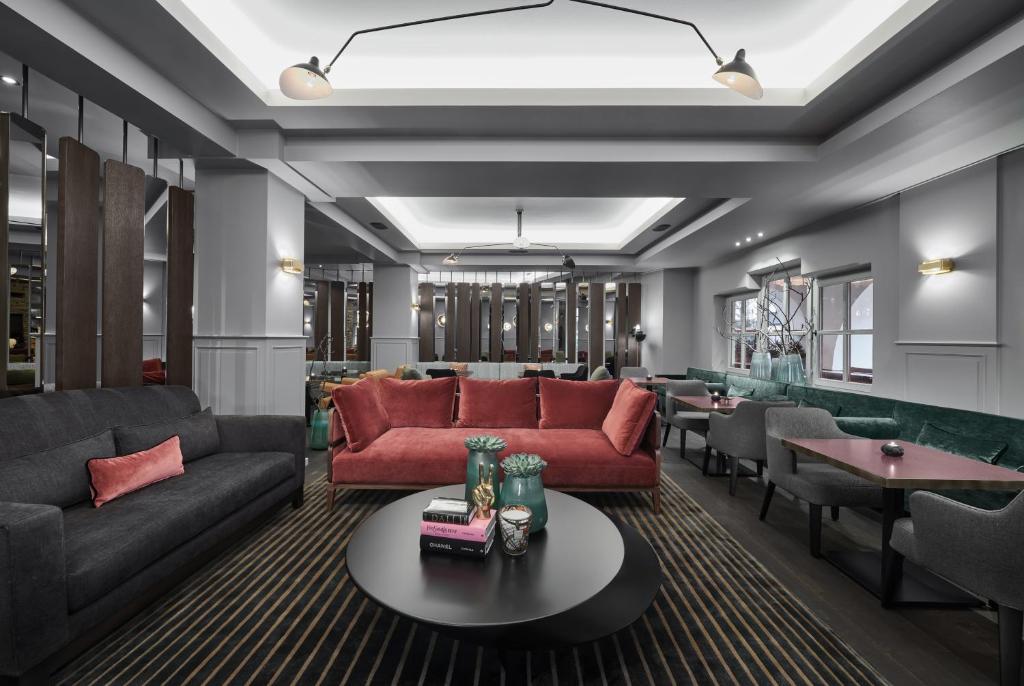 a living room with red couches and tables at Schwarzer Adler Kitzbühel - Adults Only in Kitzbühel