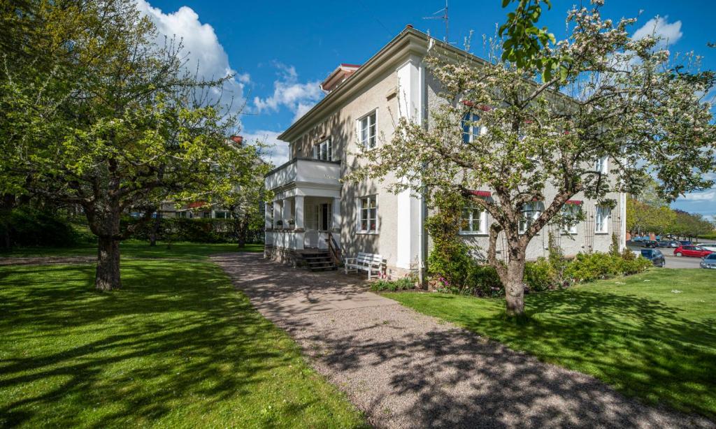 una vieja casa blanca con árboles delante de ella en Vandrarhemmet Östergatan en Skövde