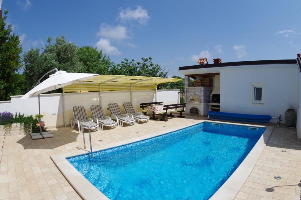 a swimming pool with chairs and a table and a house at Apartment Mia in Vinkuran
